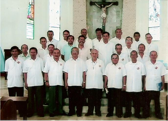 The K of C Men's choir strikes a pose at the church Altar with their choir trainor, Mr. Bogs Paderes ( in blue shirt ).